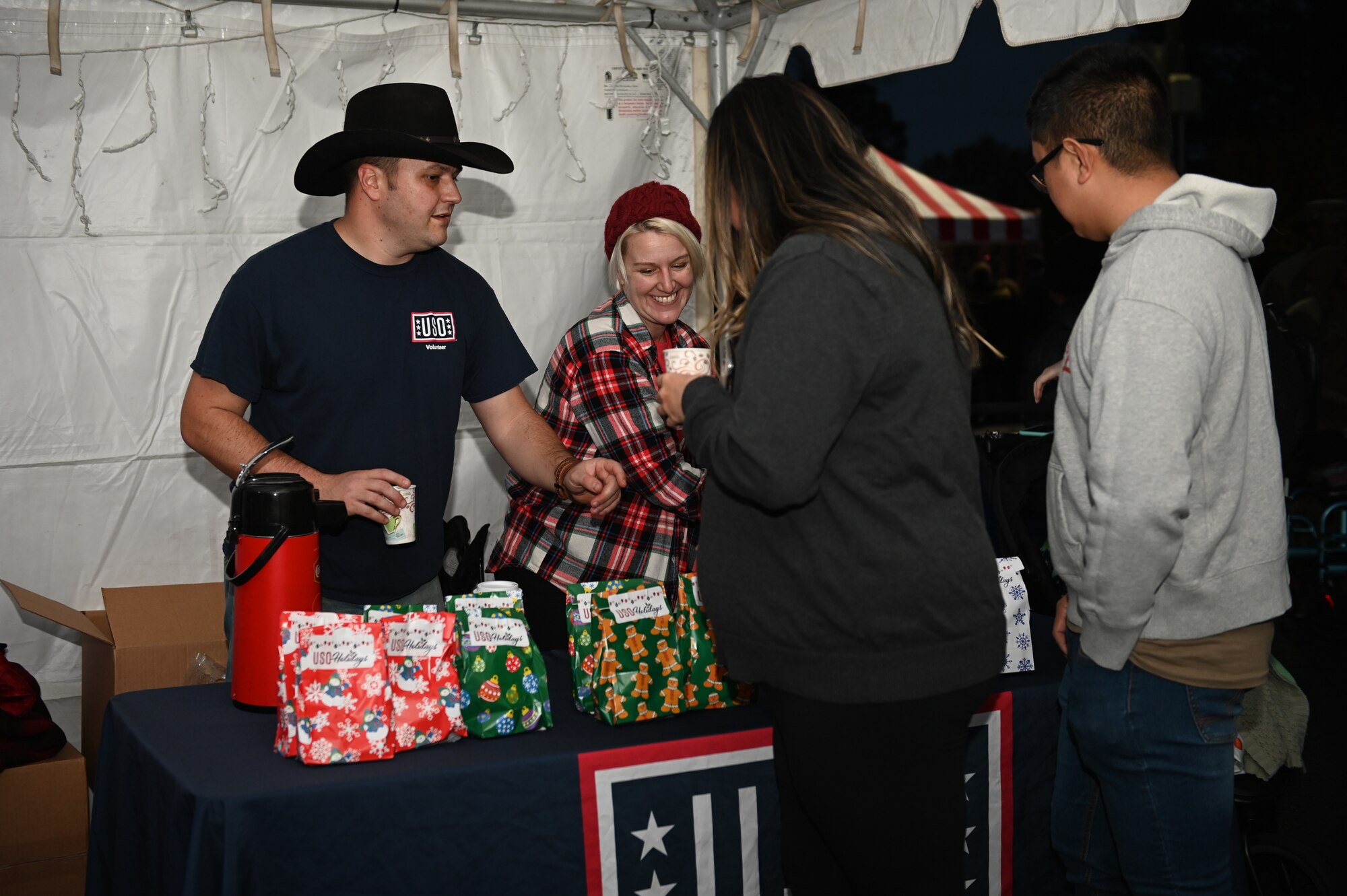 The USO volunteers hand out hot cocoa and goody bags to Airmen and their families during the Holiday Village and vendor fair at Seymour Johnson Air Force Base, North Carolina, Dec. 5, 2022. The festivities included entertainment for children, music performances, Santa and Mrs. Claus and vendor booths. (U.S. Air Force photo by Airman 1st Class Rebecca Sirimarco-Lang)