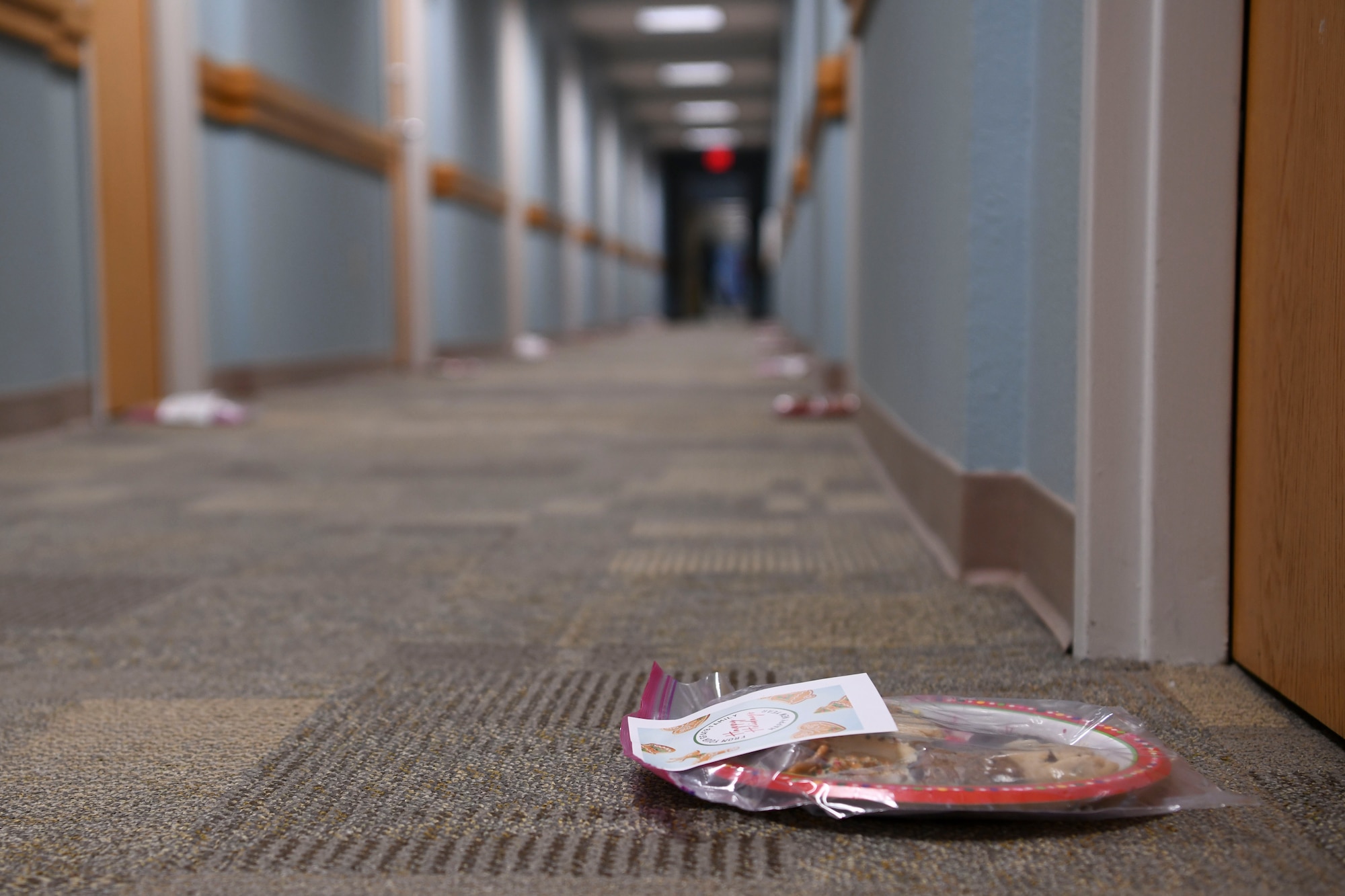 Plates of cookies sit in front of doors all the way down a long hall way.