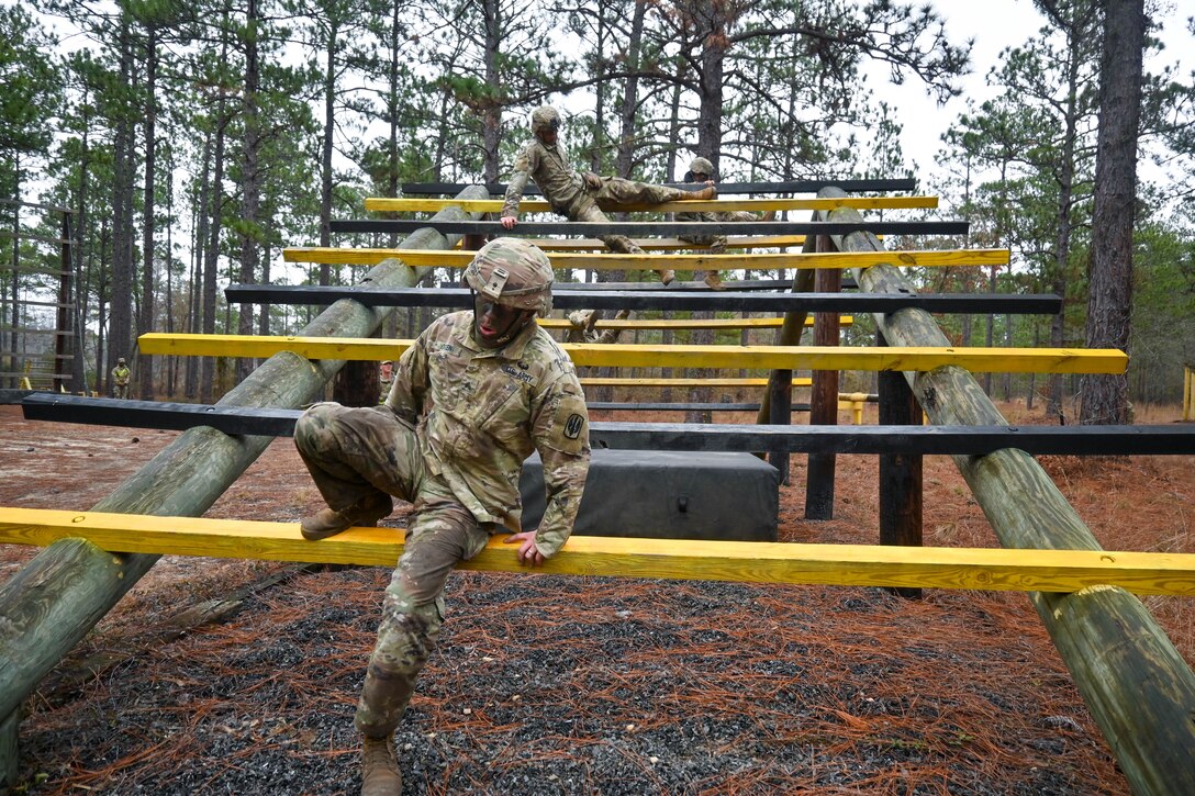 A soldier steps down from a ladder-like obstacle.