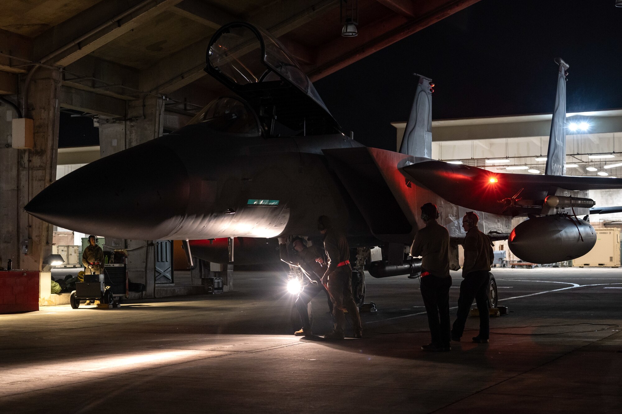 Four Airmen prepare to launch an F-15 at night.