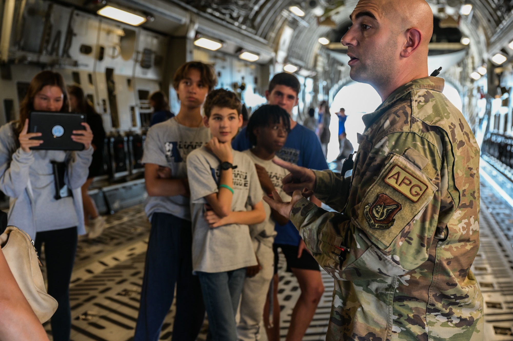 Tech. Sgt. Nicholas Giambattista, 15th Aircraft Maintenance Squadron C-17 Globemaster III crew chief, speaks to students from Aliamanu Middle School during a base tour at Joint Base Pearl Harbor-Hickam, Hawaii, Nov. 22, 2022. Active duty and Hawaii Air National Guard members highlighted their mission operations and capabilities during the showing of a C-17 static and F-22 Raptor static. (U.S. Air Force photo by Staff Sgt. Alan Ricker)