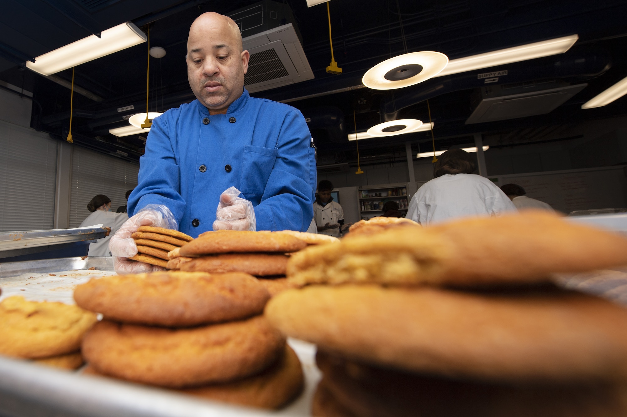 Barry Oxendine, Yokota High School culinary arts teacher, places cookies onto trays in preparation for the base’s annual Yokota Cookie Crunch at the Yokota High School located at Yokota Air Base, Japan, Dec. 8, 2022. Oxendine, with the help of his students, oversaw the baking of more than 3,500 cookies for the event to ensure service members living in the dormitories at Yokota Air Base receive treats for the holidays. (U.S. Air Force photo by Tech. Sgt. Christopher Hubenthal)