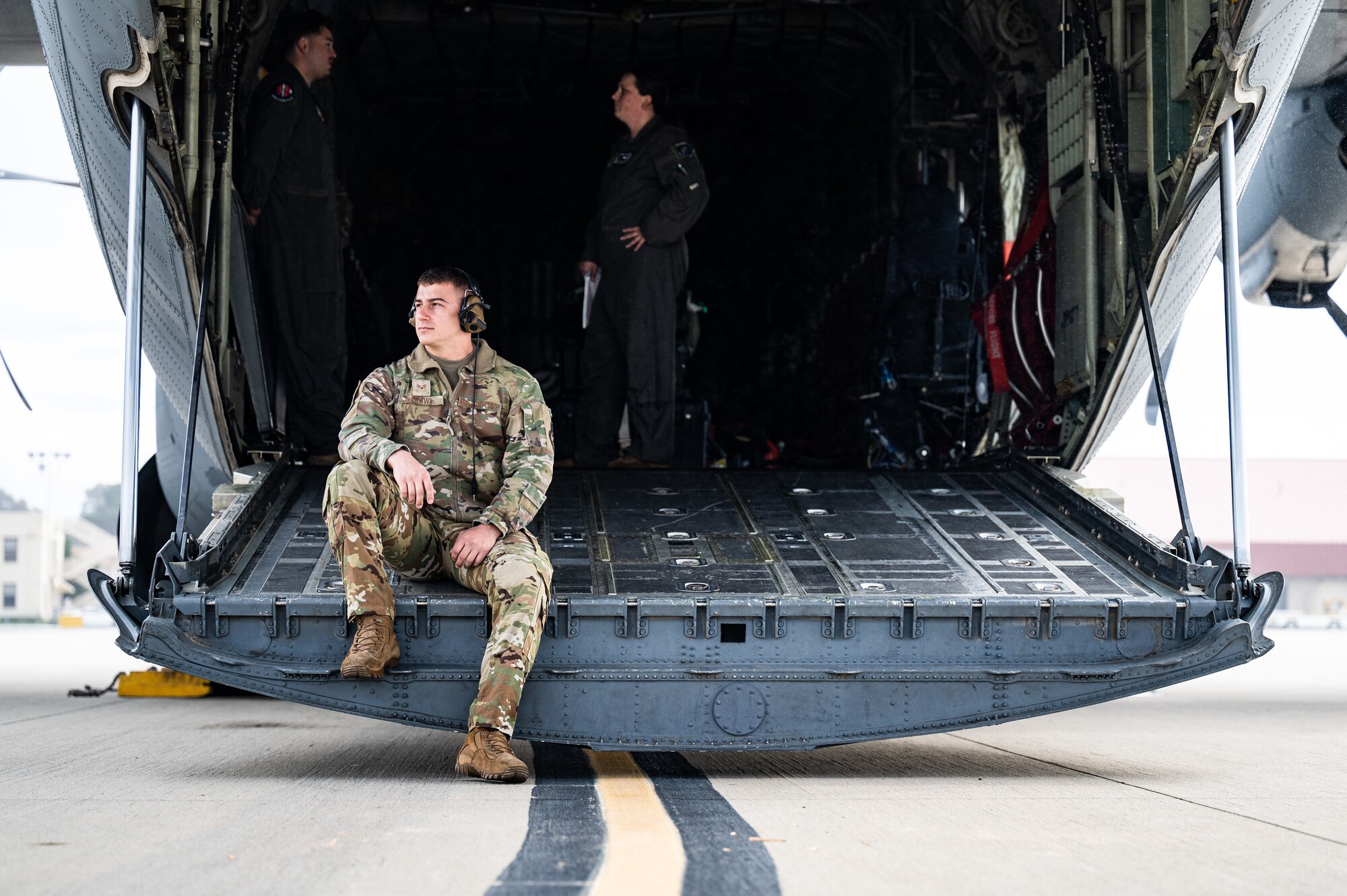 a flying crew chief waits on the back of a C-130J Hercules