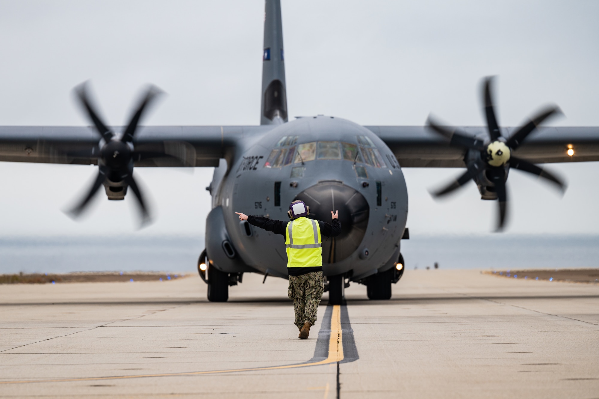 A U.S. Navy Sailor marshals a C-130J Hercules