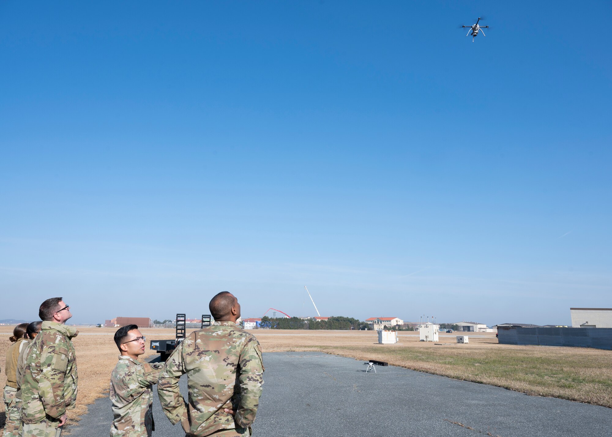 Chief Master Sgt. Alvin R. Dyer, 7th Air Force command chief (fourth from left), and Tech. Sgt. Benedic Flores, 8th Civil Engineer Squadron execution support NCO in charge (third from left), discuss and view a FLIR SkyRanger aircraft at Kunsan Air Base, Republic of Korea, Dec. 8, 2022. The FLIR SkyRanger aircraft allows Kunsan engineers to rapidly assess the airfield when called upon. (U.S. Air Force photo by Staff Sgt. Isaiah J. Soliz)