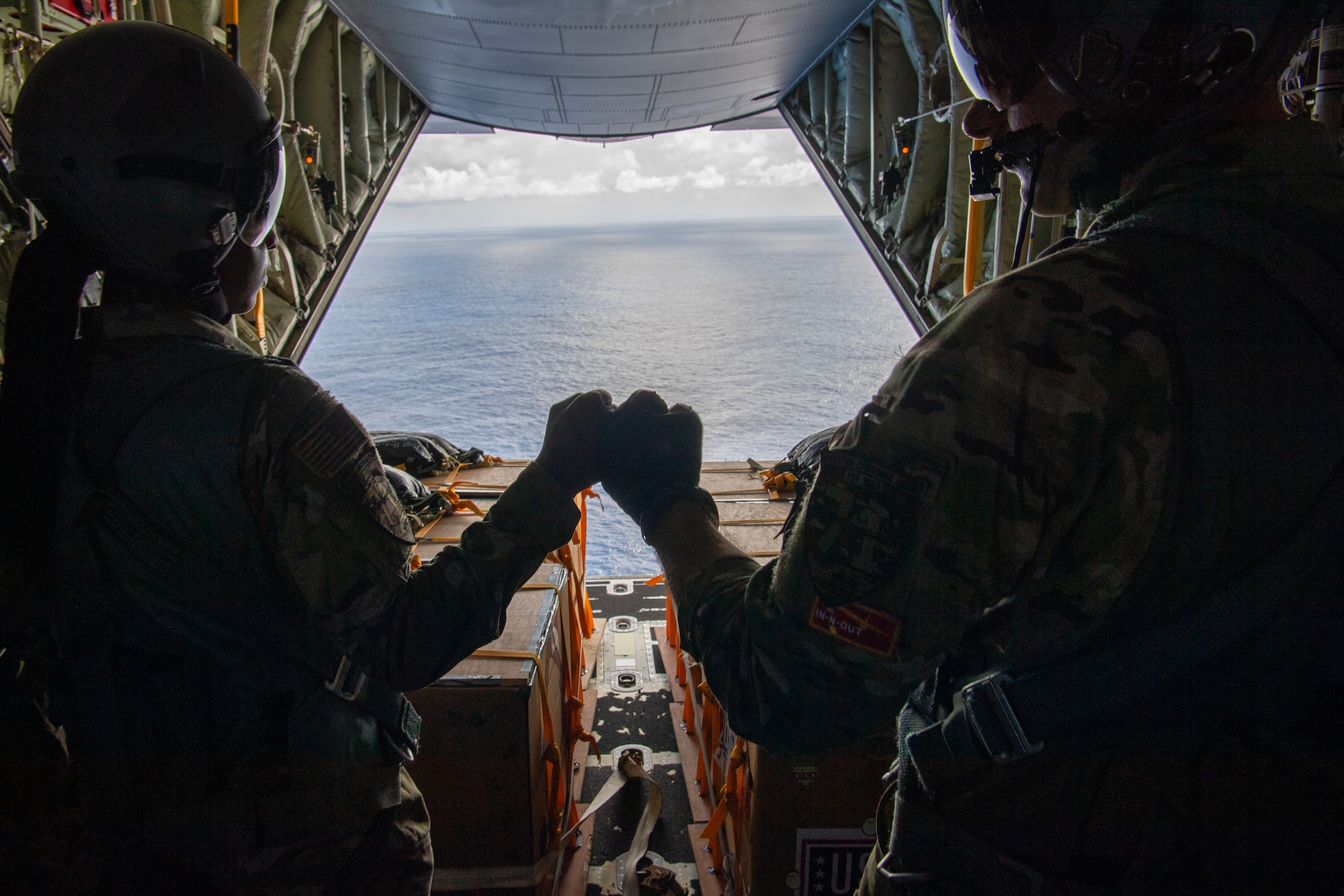 U.S. Air Force Airmen fist bump in a C-130J Super Hercules