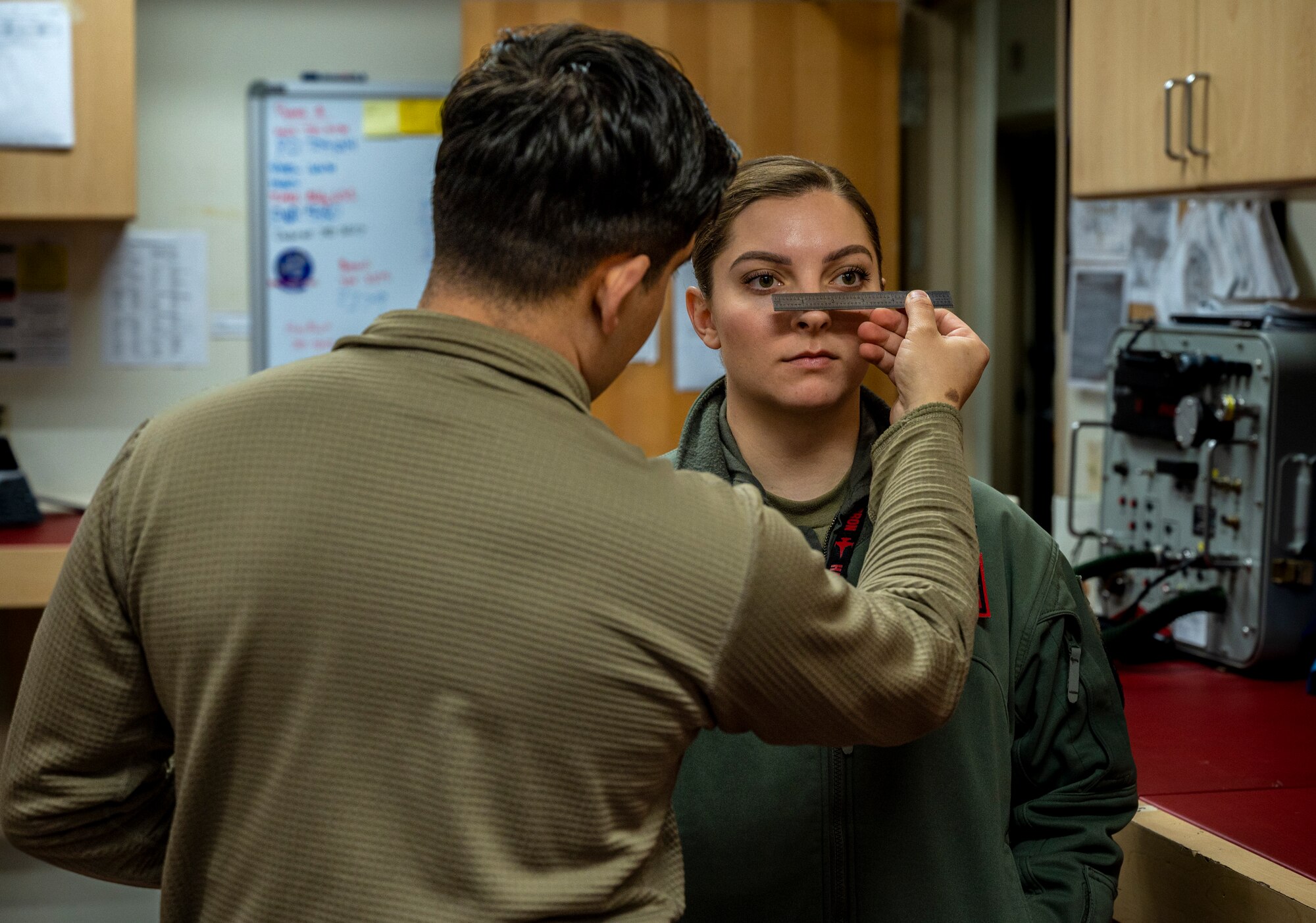 U.S. Air Force Tech. Sgt. Humberto Morales, 51st Operations Support Squadron NCO in charge of aircrew flight equipment, measures the distance between the pupils of 1st Lt. Abby Maio, 36th Fighter Squadron pilot, at Osan Air Base, Republic of Korea, Dec. 8, 2022.