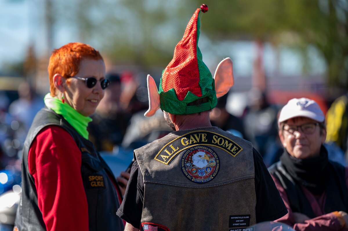 A person wearing a Christmas elf ear hat converses with people.