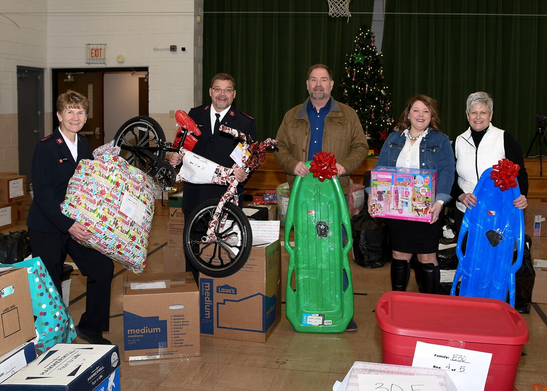 A group of men and women post for a photo with gifts donated for the 2022 Adopt-a-Family program.