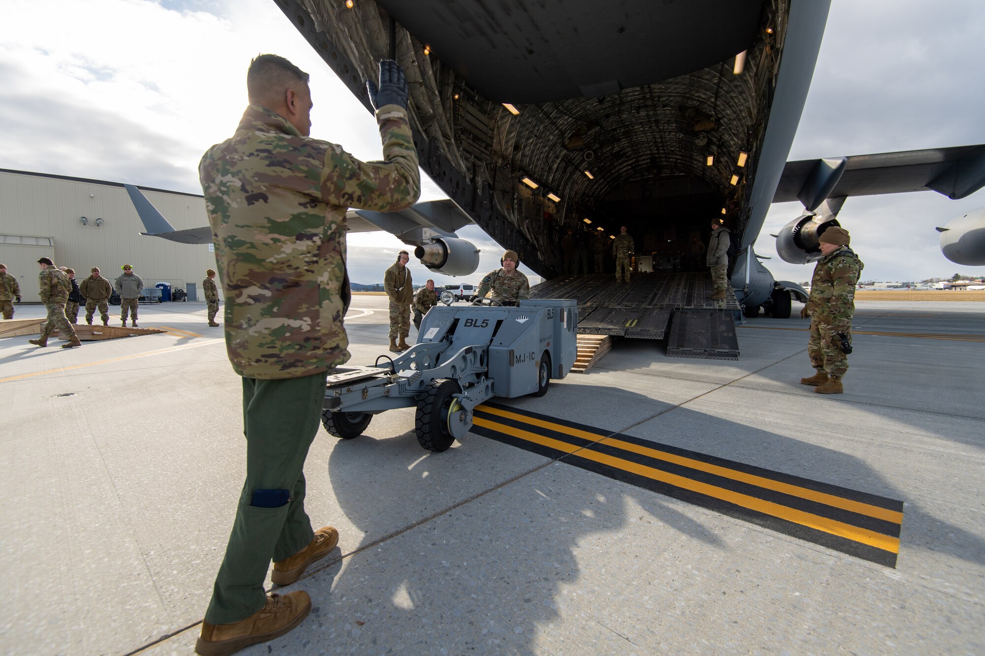 Airmen from the Vermont Air National Guard's 158th Aircraft Maintenance Squadron, along with Airmen from the New York ANG's 105th Airlift Wing, Stewart Air National Guard Base in Newburgh, New York, position wooden ramps to assist with loading equipment onto a C-17 Globemaster III aircraft at the Vermont Air National Guard Base, South Burlington, Vermont, Dec. 4, 2022. The multi-capable Airmen concept entails training Airmen in basic tasks outside of their usual specialty, so by having 158th Fighter Wing Airmen receiving exposure and training from the 105th, allows the Vermonters to be more versatile and contribute to the mission where needed. (U.S. Air National Guard photo by Senior Master Sgt. Michael Davis)