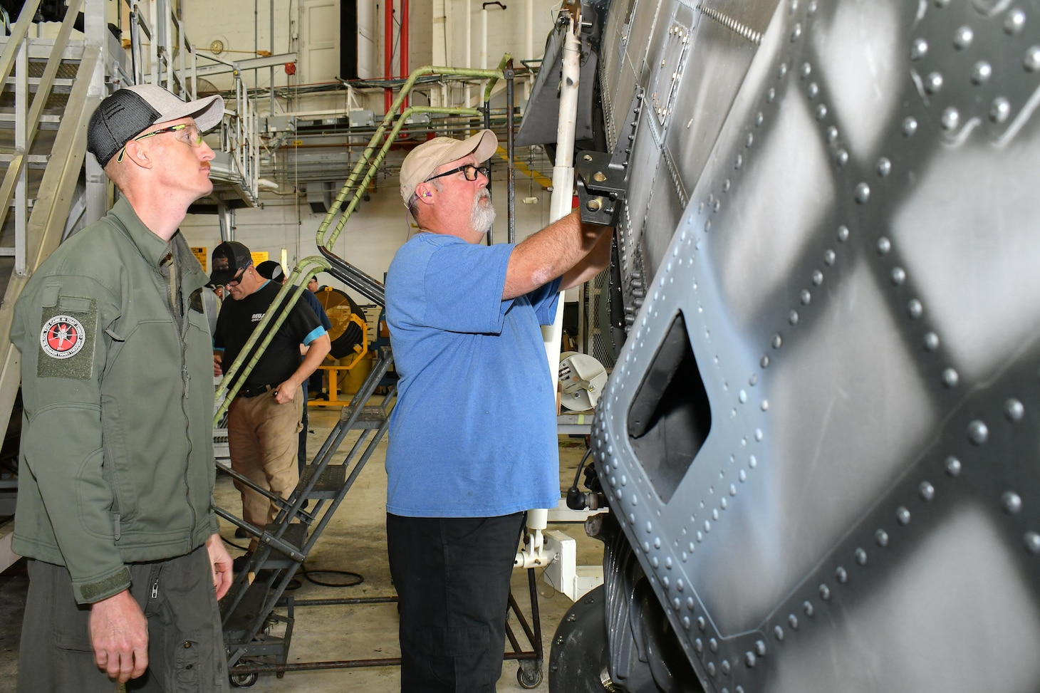 Fleet Readiness Center East (FRCE) H-53 Military Branch head and CH-53 pilot Capt. Ryan Boyer, left, and Aaron Bennett, an aircraft examiner at FRCE, conduct a flight control inspection on a tail pylon for a CH-53 helicopter.