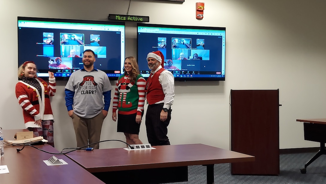 Four people pose in a variety of Ugly Christmas sweaters.