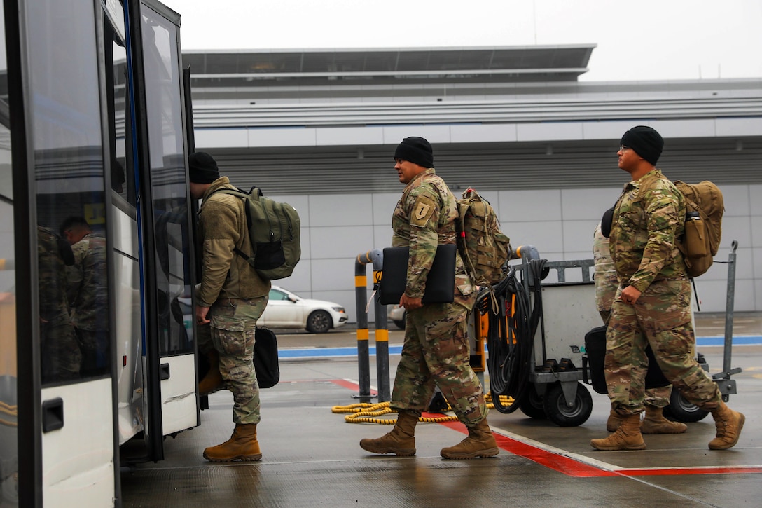 Soldiers board a shuttle at an airport.