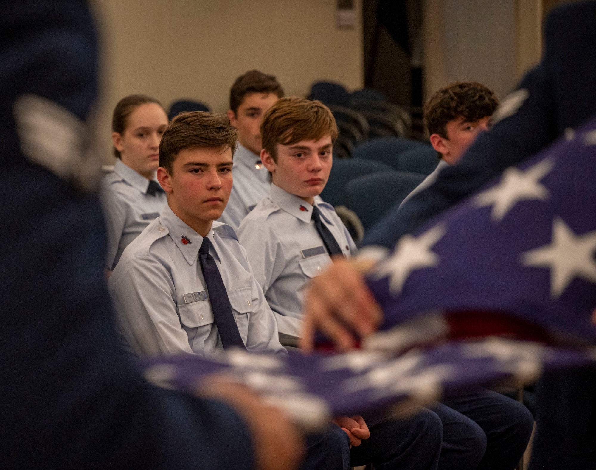 Goldsboro Civil Air Patrol cadets watch the 4th Fighter Wing Honor Guard perform a flag folding ceremony at Seymour Johnson Air Force Base, North Carolina, Dec. 7, 2022. The event boosted community relationships, promoted Air Force heritage and helped develop leaders. (U.S. Air Force photo by Airman 1st Class Sabrina Fuller)
