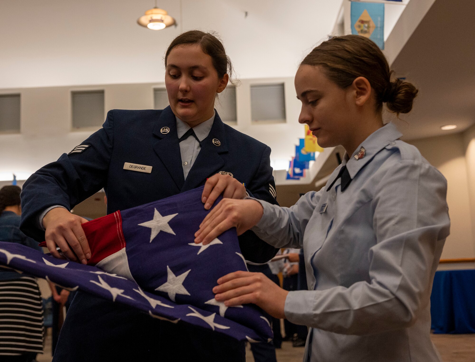 Senior Airman Chloe Degrande, 4th Equipment Maintenance Squadron non-destructive inspector and base honor guard member, shows Anna Stanmire, a Goldsboro Civil Air Patrol cadet, how to fold a flag at Seymour Johnson Air Force Base, North Carolina, Dec. 7, 2022.  The event taught the cadets about the base honor guard responsibilities in a variety of ceremonies, history and traditions. (U.S. Air Force photo by Airman 1st Class Sabrina Fuller)