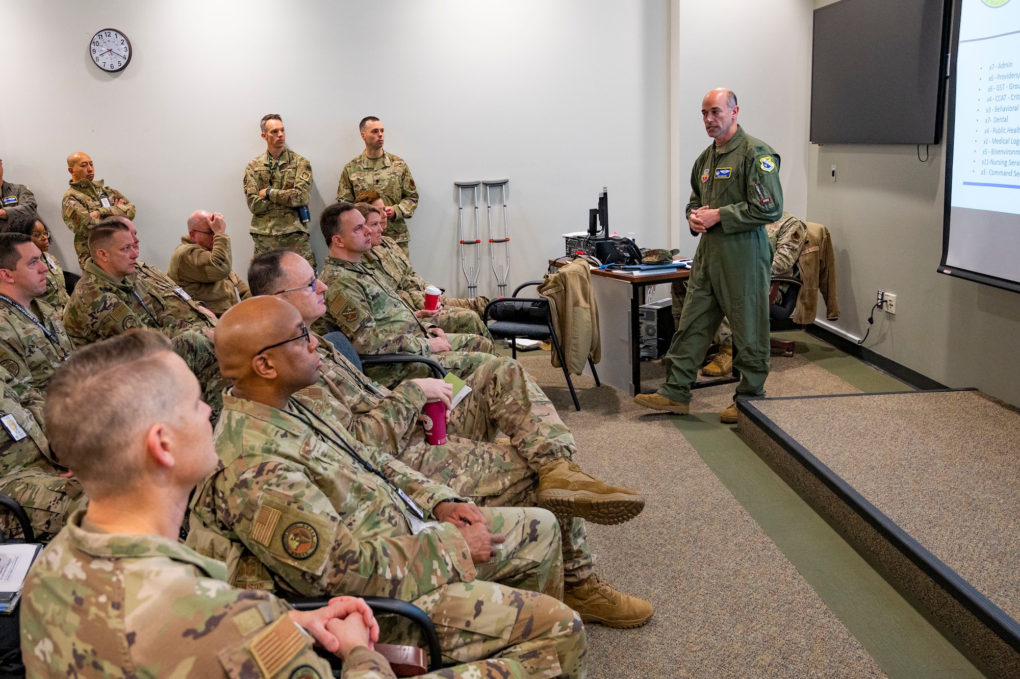 Uniformed military officer addresses assembled group of uniformed military members.