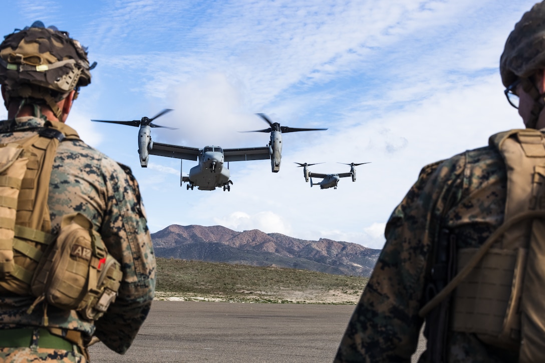 U.S. Marines with Lima Company, 3rd Battalion, 1st Marine Regiment, 1st Marine Division, watch MV-22B Ospreys with Marine Medium Tiltrotor Squadron 164, Marine Aircraft Group 39, 3rd Marine Aircraft Wing, approach a landing zone prior to conducting an air assault as part of Steel Knight 23 at Marine Corps Base Camp Pendleton, California, Dec. 5, 2022. Steel Knight is an annual combined arms live-fire exercise which ensures 1st MARDIV is optimized for naval expeditionary warfare in contested spaces, and is purpose-built to facilitate future operations afloat and ashore. (U.S. Marine Corps photo by Lance Cpl. Daniel)