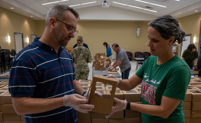 Jason Bateman, president of the Team Charleston Key Spouses Club, left, and Adrienne Lankford, a volunteer, place cookies and a letter into a box.