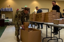 U.S. Air Force Master Sgt. John Plumley, 628th Logistics Readiness Squadron first sergeant, places boxes of holiday cookies into a box.