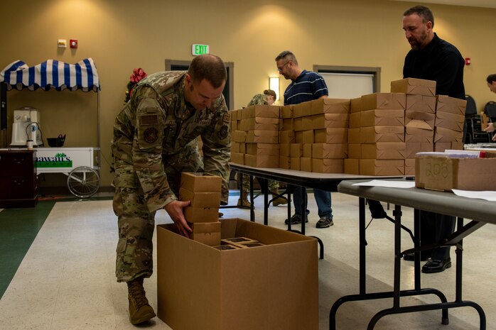 U.S. Air Force Master Sgt. John Plumley, 628th Logistics Readiness Squadron first sergeant, places boxes of holiday cookies into a box.