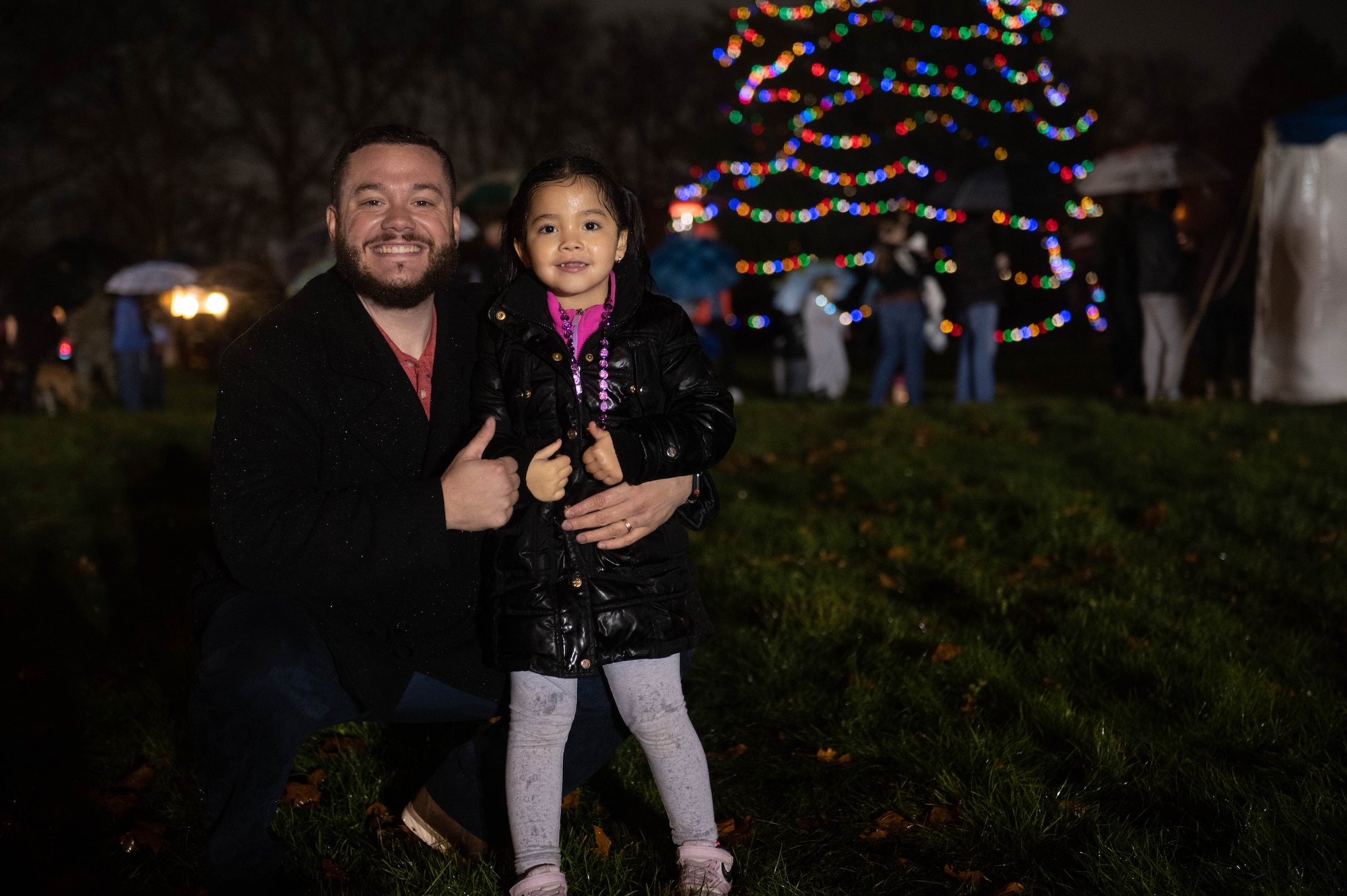 A father and daughter pose in front of the Christmas tree during the annual JB MDL holiday tree lighting ceremony on Joint Base McGuire-Dix-Lakehurst, N.J., Dec. 6, 2022. The annual JB MDL holiday tree lighting ceremony featured a variety of festivities, such as: horse-and-carriage rides, funnel cakes, pretzels, hot chocolate, and meeting in-person with Mr. and Mrs. Claus. The annual tree lighting ceremony is an opportunity for JB MDL families to come together at the start of the holiday season. (U.S. Air Force photo by Senior Airman Faith Iris MacIlvaine)