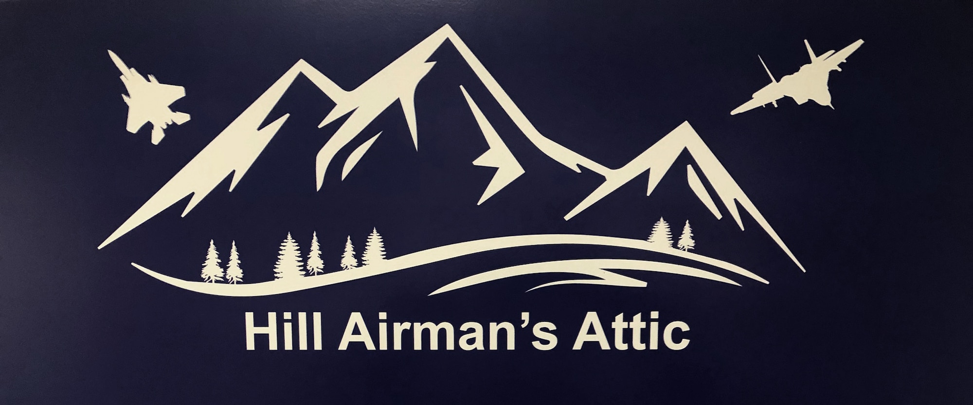 The sign that stands outside the airman's Attic. Mountains with two F-35s flying by.