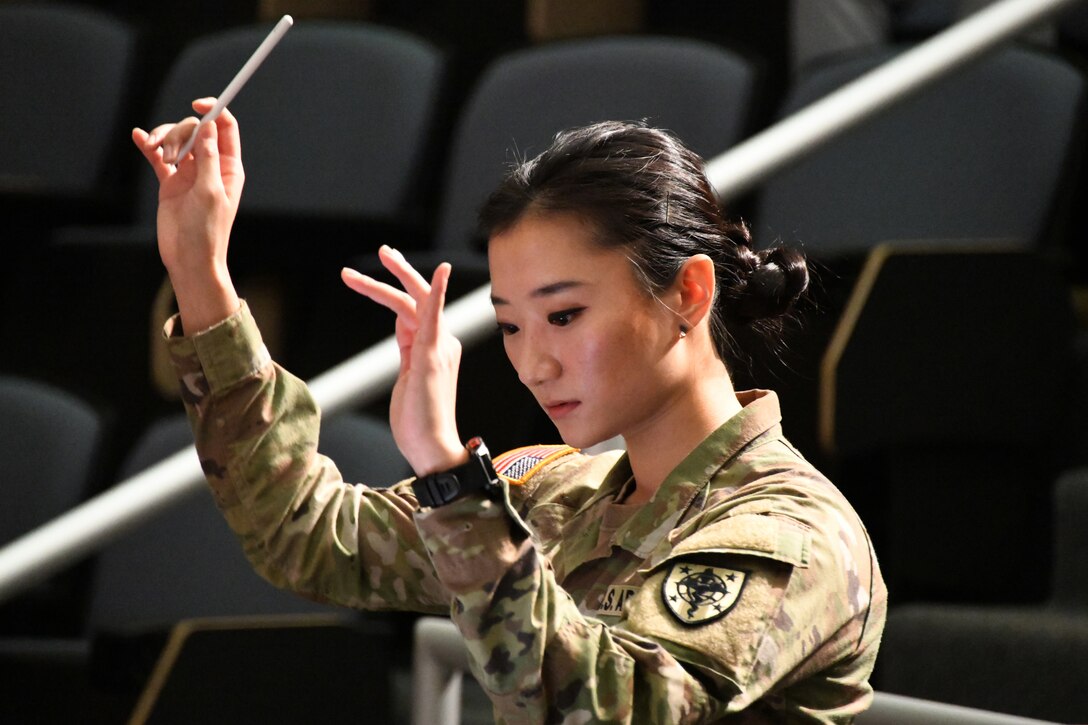 A service member, standing, holds a baton.