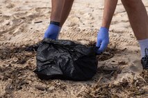 A participant with the Young Marine program collects debris during a base-wide beach clean-up, Marine Corps Base Hawaii, Dec. 2, 2022. The Young Marines participated in a base-wide beach clean-up as well as several other committee events, while participating and attending commemoration ceremonies of the 81st anniversary of the attacks on Pearl Harbor. (U.S. Marine Corps photo by Lance Cpl. Chandler Stacy)