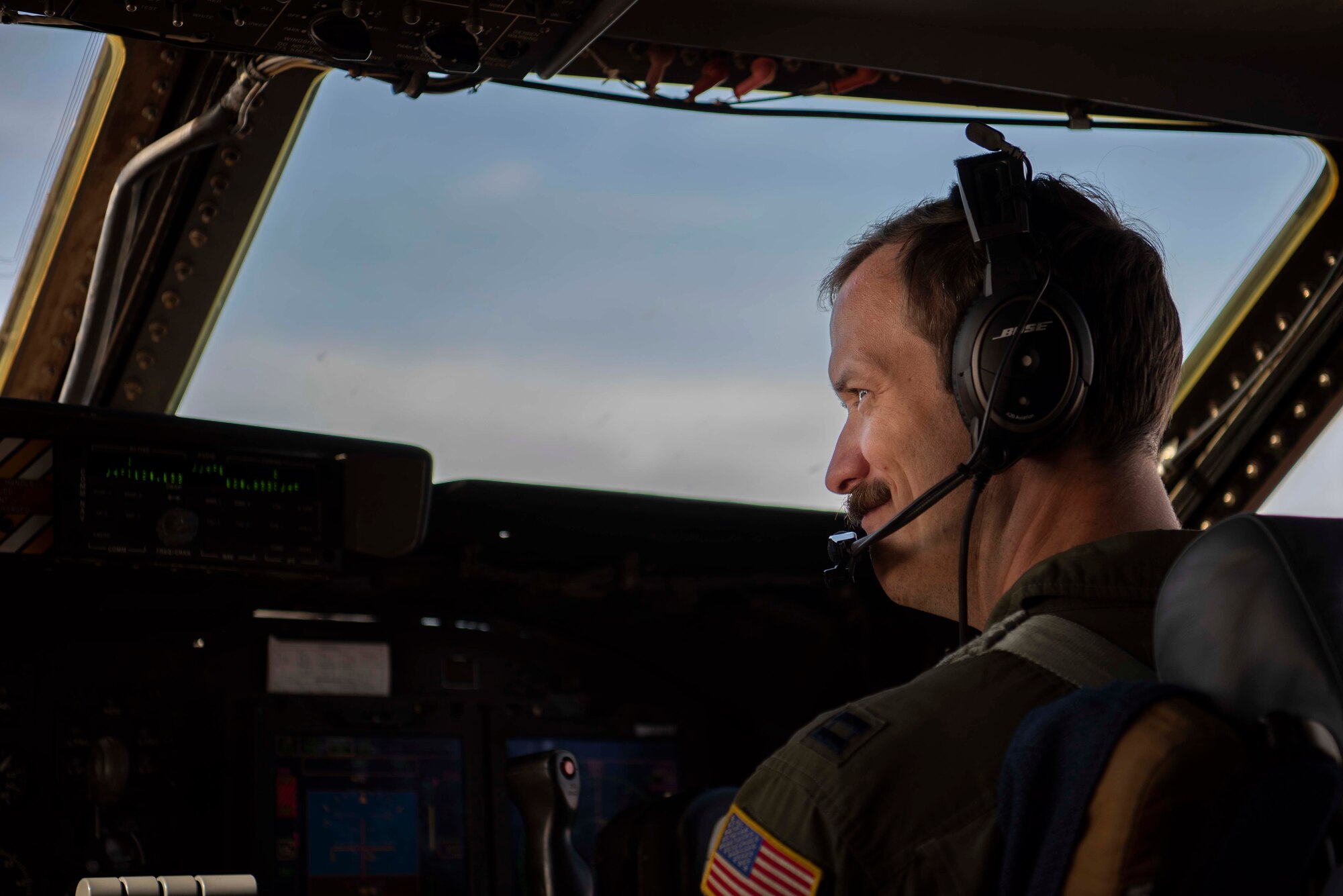 An Airman sits in the flight deck of a large aircraft in flight