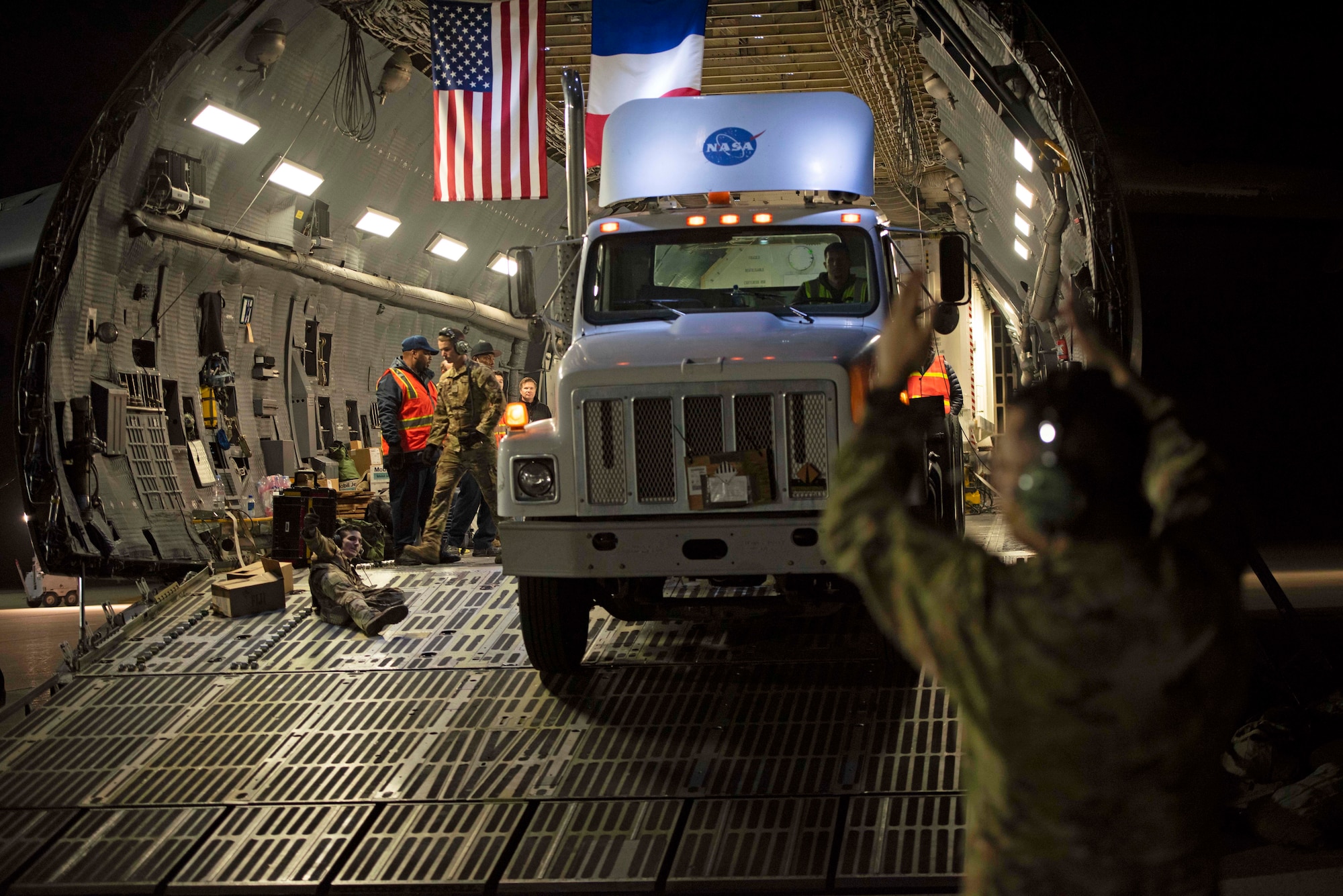 An airman guides a truck out of an aircraft.
