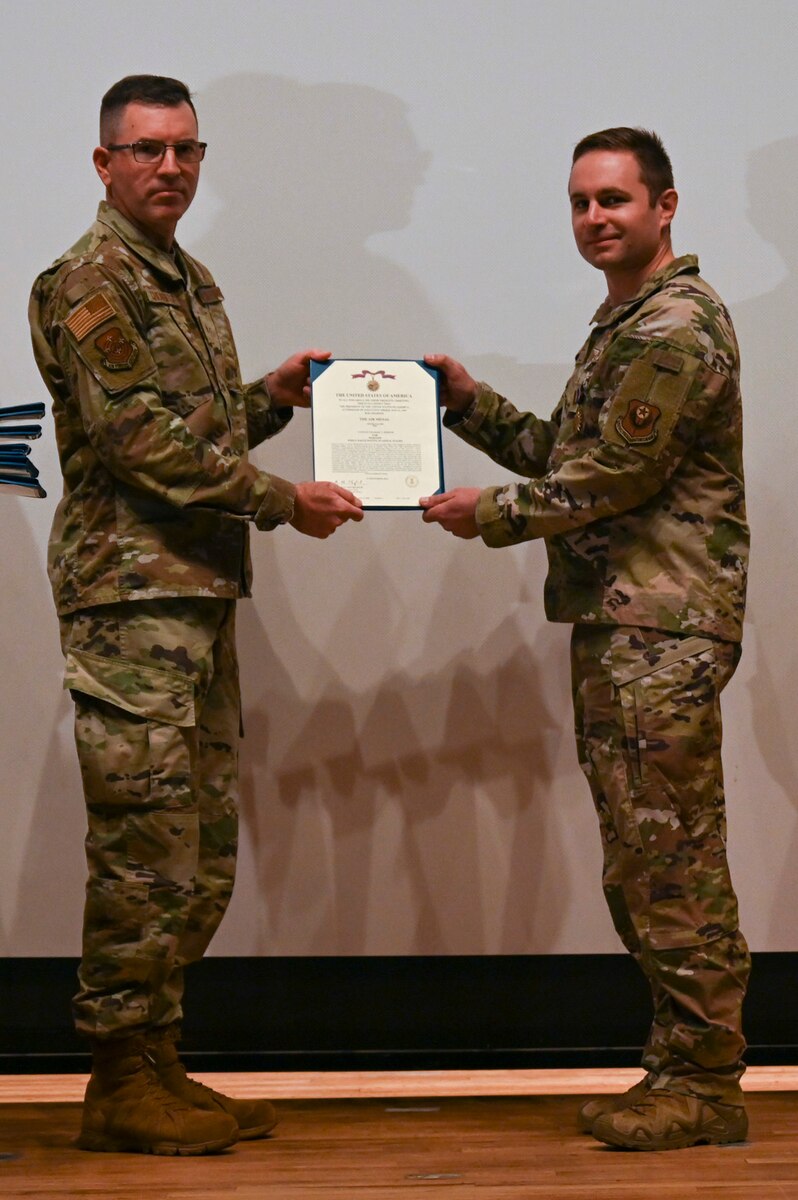 A photo of a man in a military uniform being handed a certificate from another man in a military uniform.