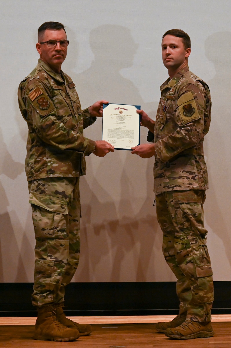 A photo of a man in a military uniform being handed a certificate from another man in a military uniform.