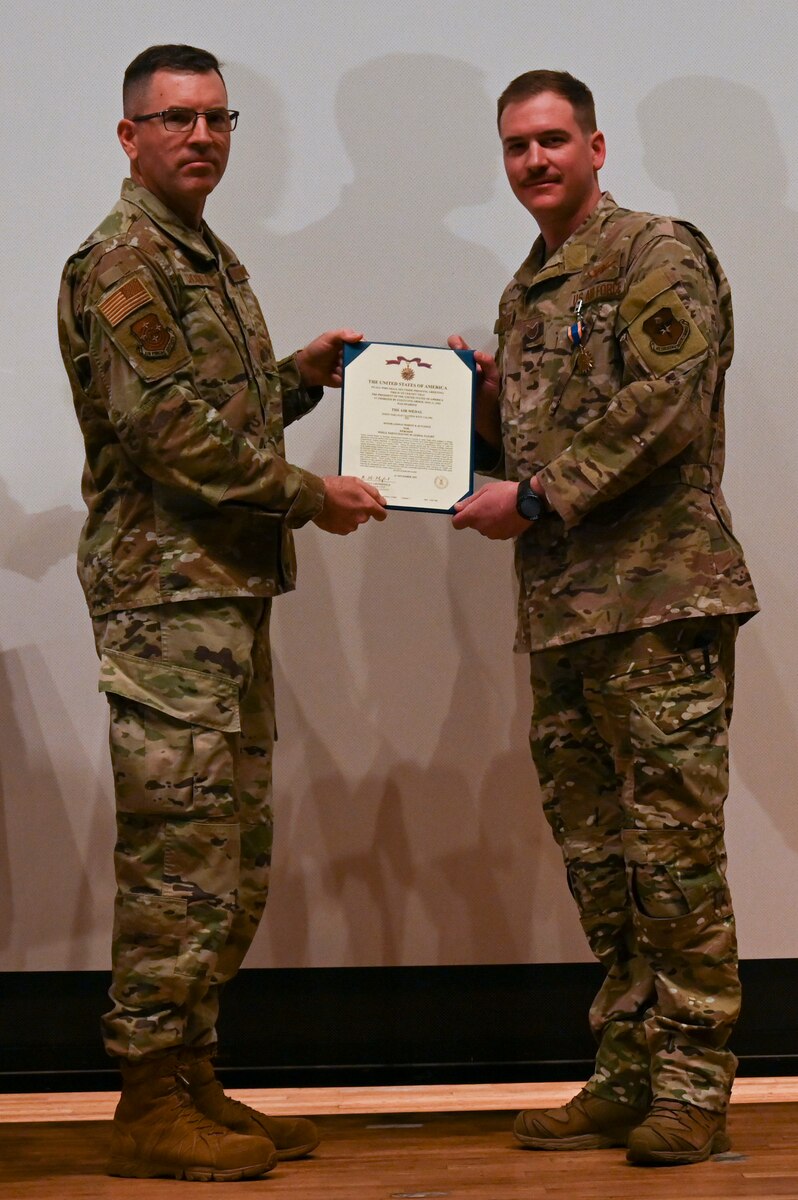 A photo of a man in a military uniform receives a certificate from another man in uniform.