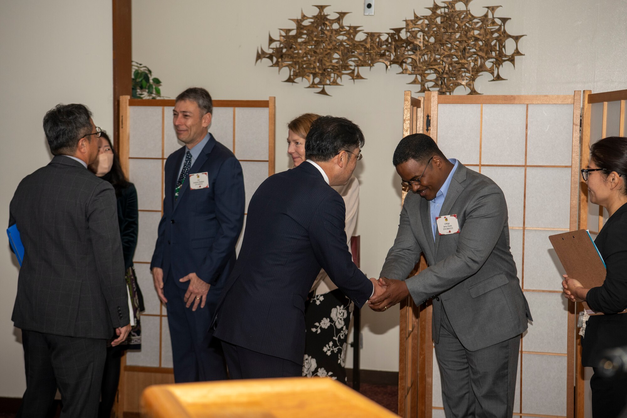 two people greet each other and exchange a bow and handshake.