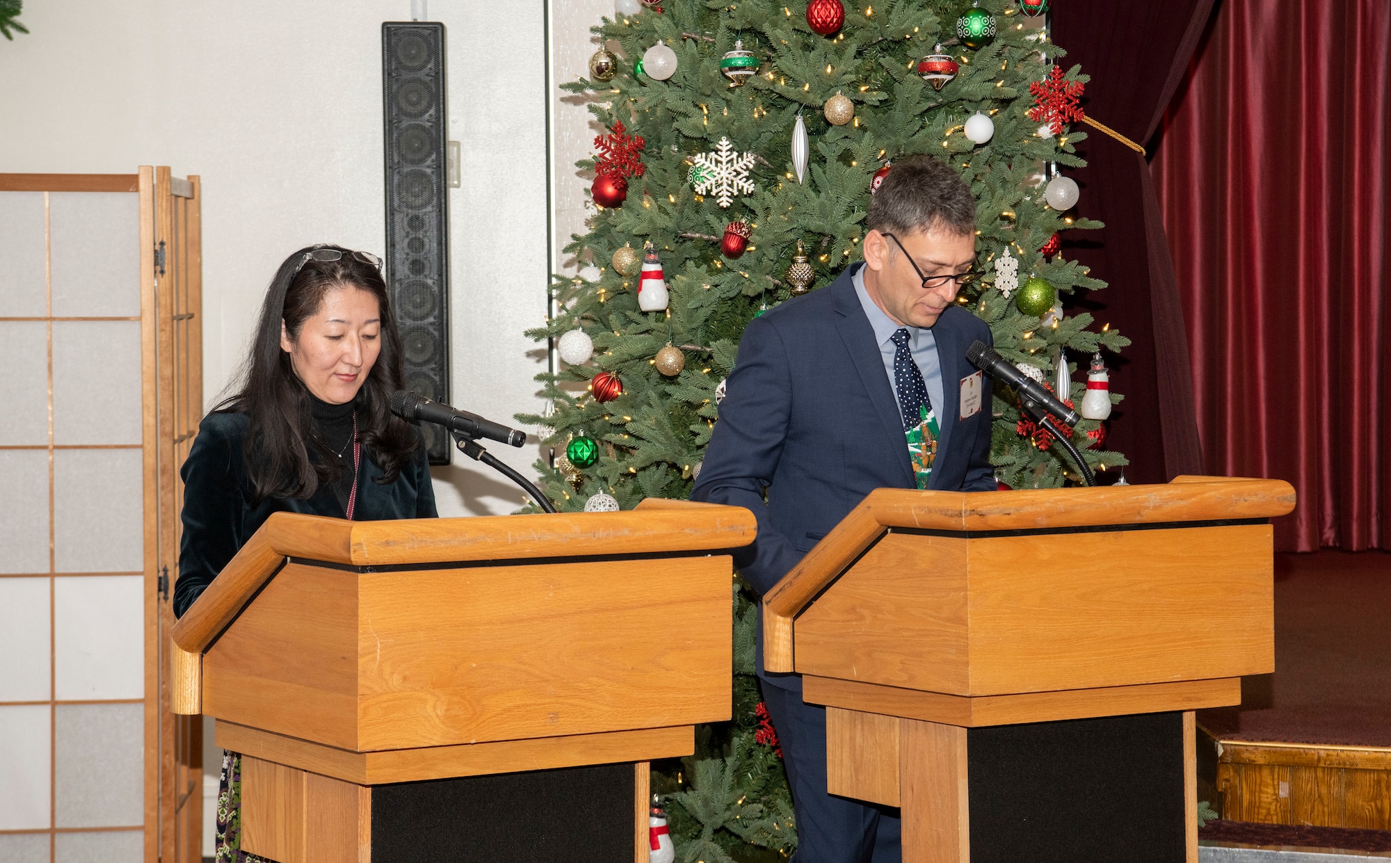 a person and their translator speaking to the attendees of a holiday social event.