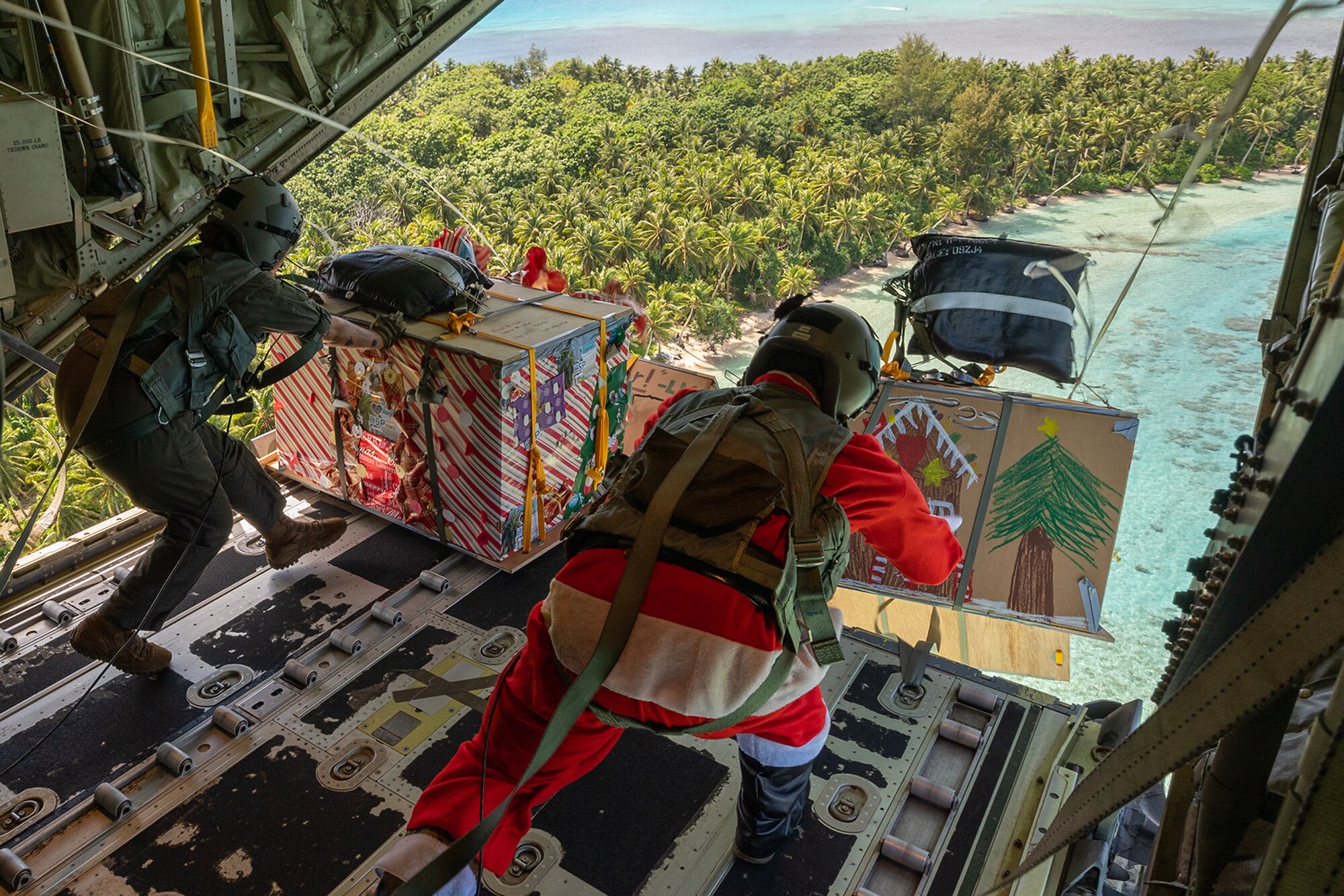 U.S. Air Force Airmen push four humanitarian aid bundles out of a C-130J Super Hercules