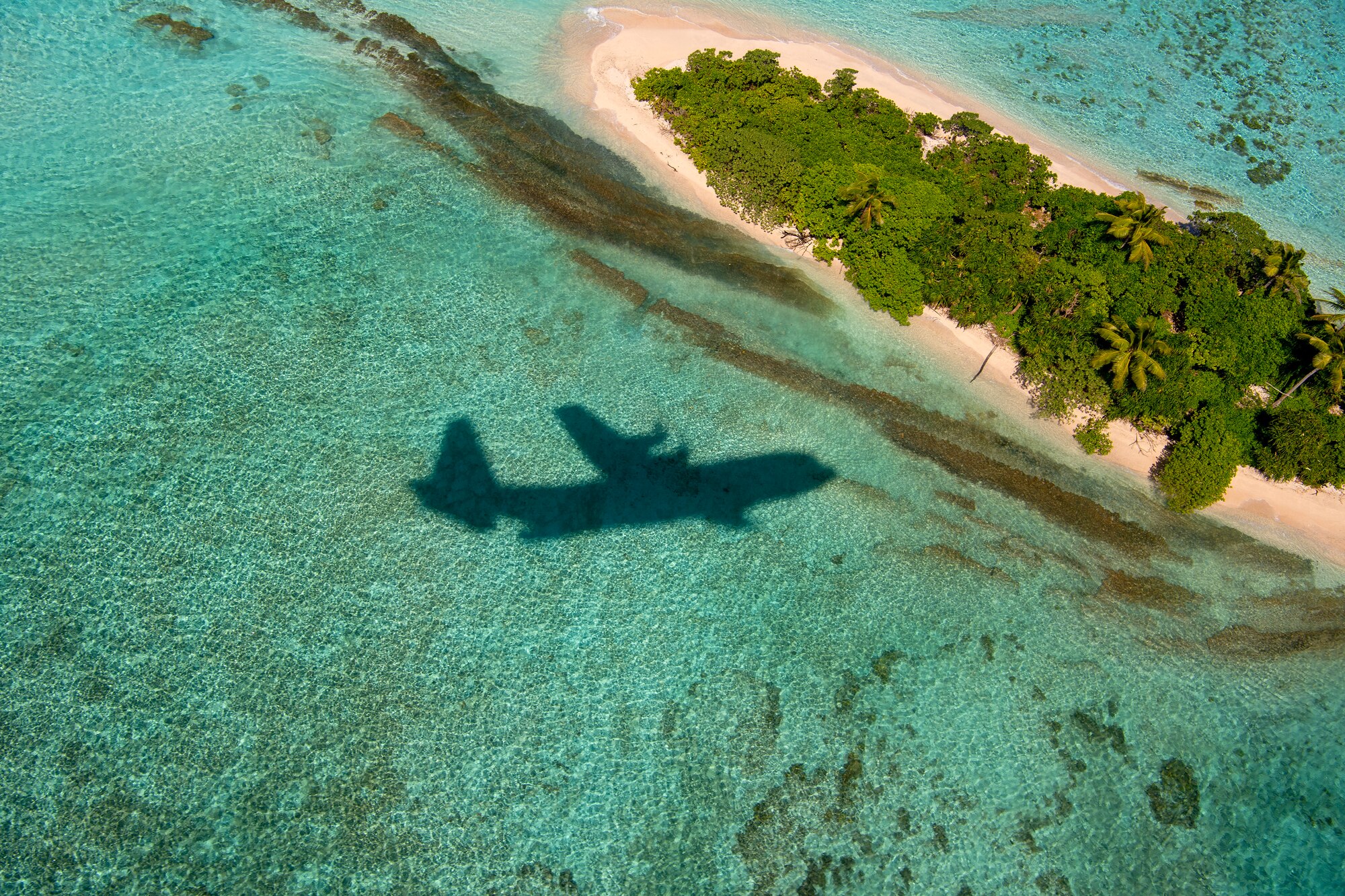 A C-130J Super Hercules flies over the water
