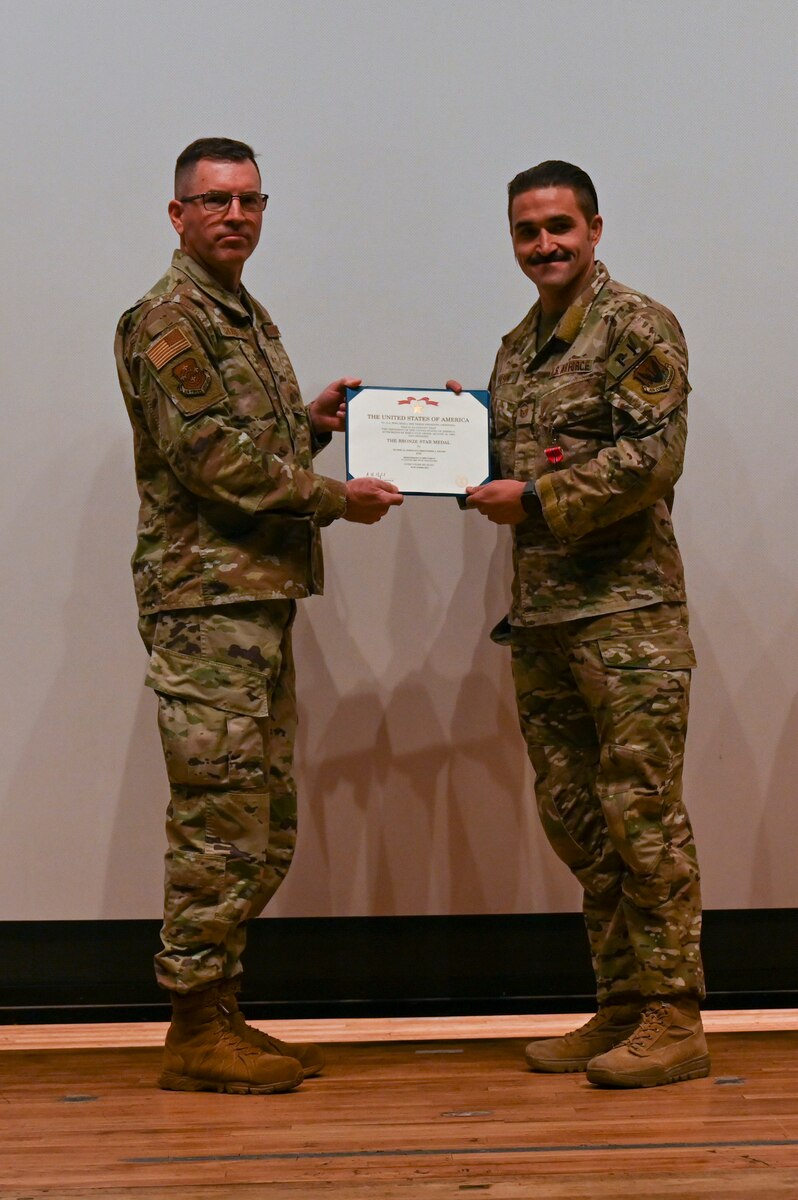 A photo of a man in a military uniform receives a certificate from another man in uniform.