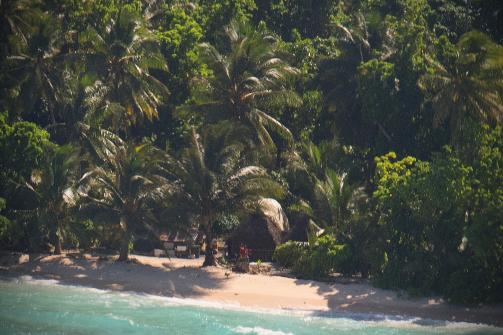 Micronesian locals wave to a C-130J Super Hercules’ aircrew from a small island