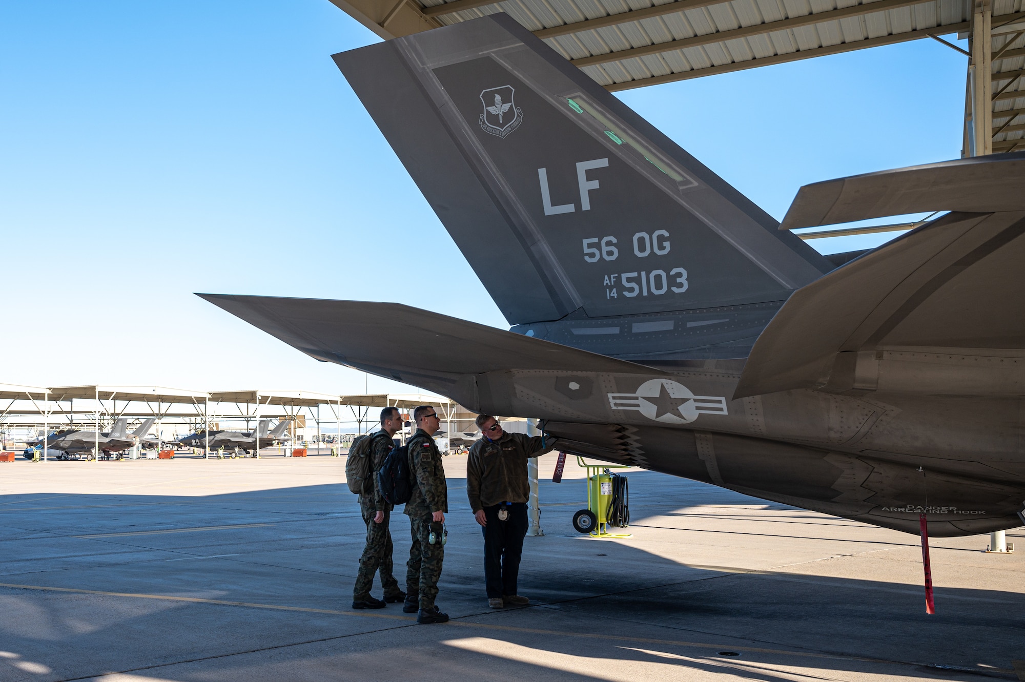 U.S. Air Force Tech. Sgt. Jeremy Buben, 62nd Aircraft Maintenance Unit F-35 Lightning II crew chief (right), briefs Polish Air Force Lt. Col. Pawal Muzyczuk, logistics officer (center), and PAF Lt. Col. Rafal Zawadka, specialist officer (left), on F-35 maintenance operations Dec. 9, 2022, at Luke Air Force Base, Arizona.