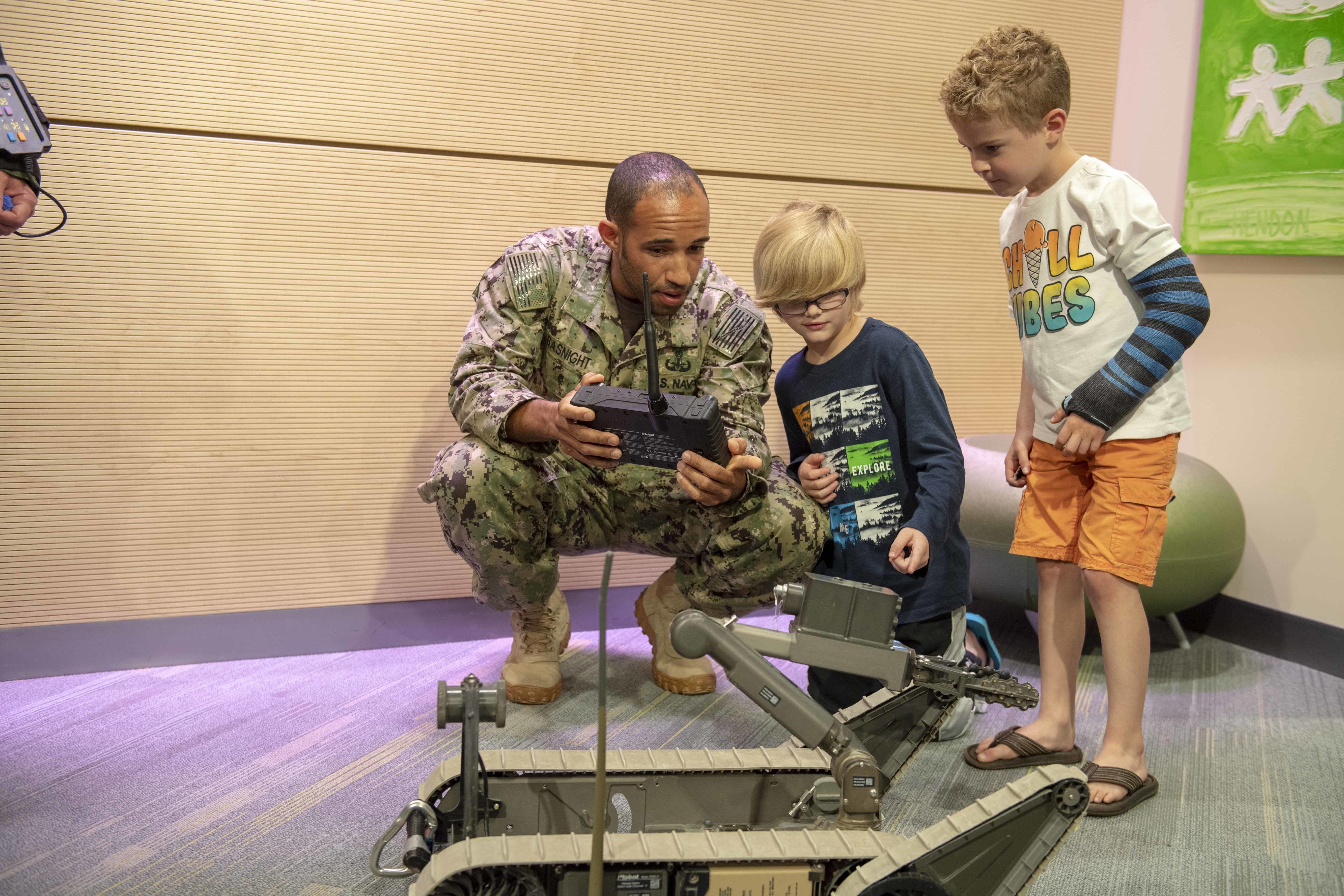 Sailor teaches children how to operate a bomb disposal robot.