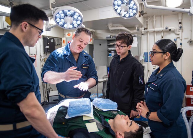 221210-N-WU964-1224 PHILIPPINE SEA (Dec. 10, 2022) Lt. Cmdr. Christopher Foran, center, from Danville, Illinois, reviews surgical procedures with Sailors during a mass casualty drill at the main medical battle dressing station of the U.S. Navy’s only forward-deployed aircraft carrier, USS Ronald Reagan (CVN 76), in the Philippine Sea, Dec. 10. Ronald Reagan, the flagship of Carrier Strike Group 5, provides a combat-ready force that protects and defends the United States, and supports Alliances, partnerships and collective maritime interests in the Indo-Pacific region. (U.S. Navy photo by Mass Communication Specialist 3rd Class Dallas A. Snider)