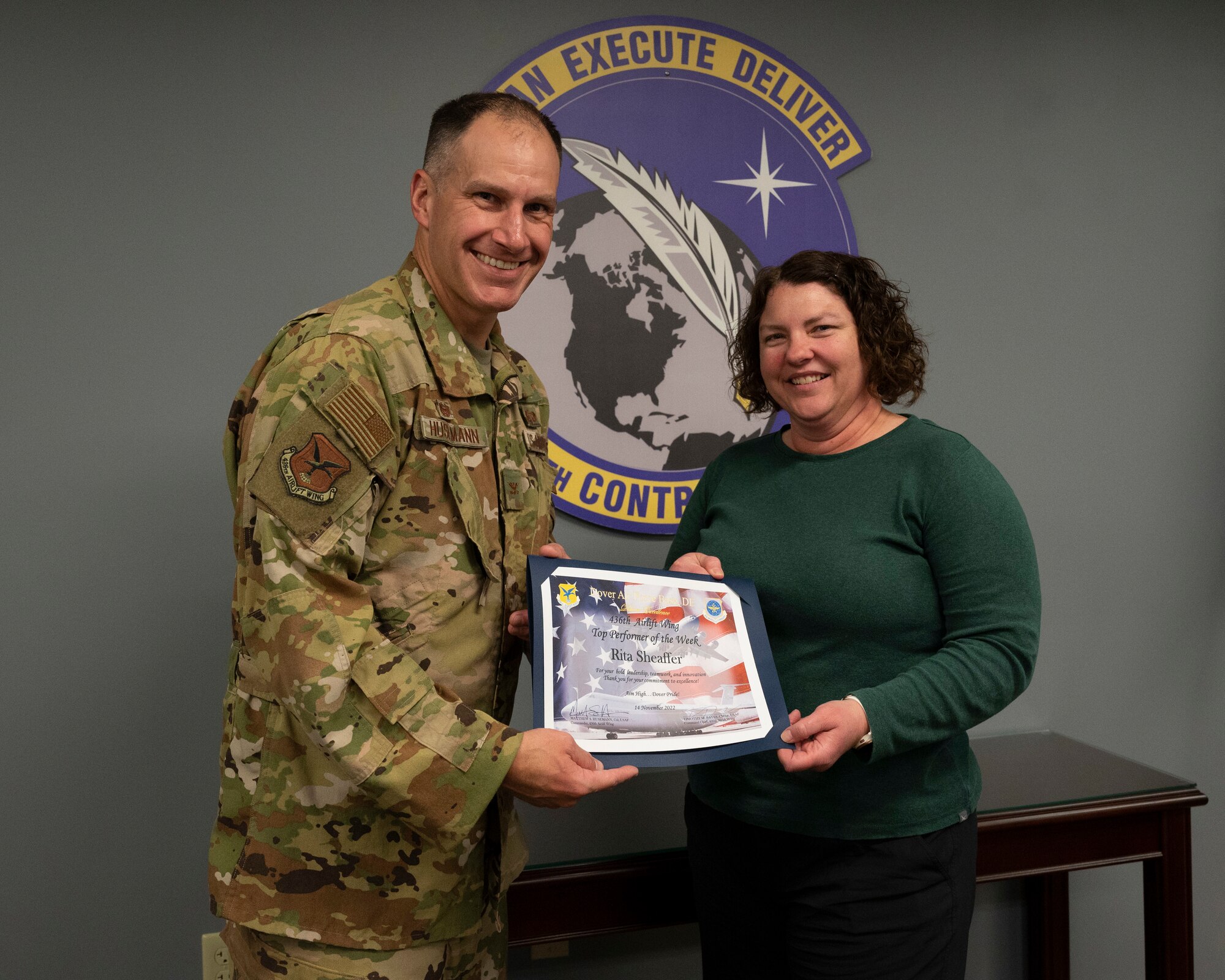 Col. Matt Husemann, left, 436th Airlift Wing commander, presents Rita Sheaffer, right, 436th Contracting Squadron administrative assistant, with a certificate recognizing her as the 436th AW Top Performer of the Week on Dover Air Force Base, Delaware, Dec. 5, 2022. Sheaffer was nominated for this award for her outstanding performance by her co-workers at the 436th CONS. (U.S. Air Force photo by Airman 1st Class Amanda Jett)