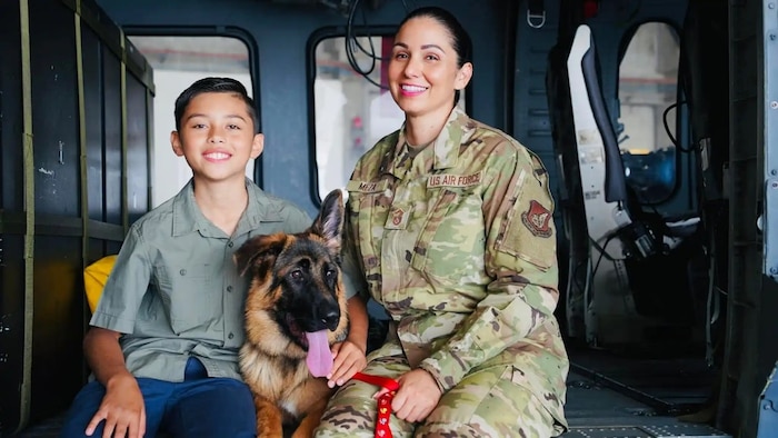Airman sitting in a helicopter with her son and dog