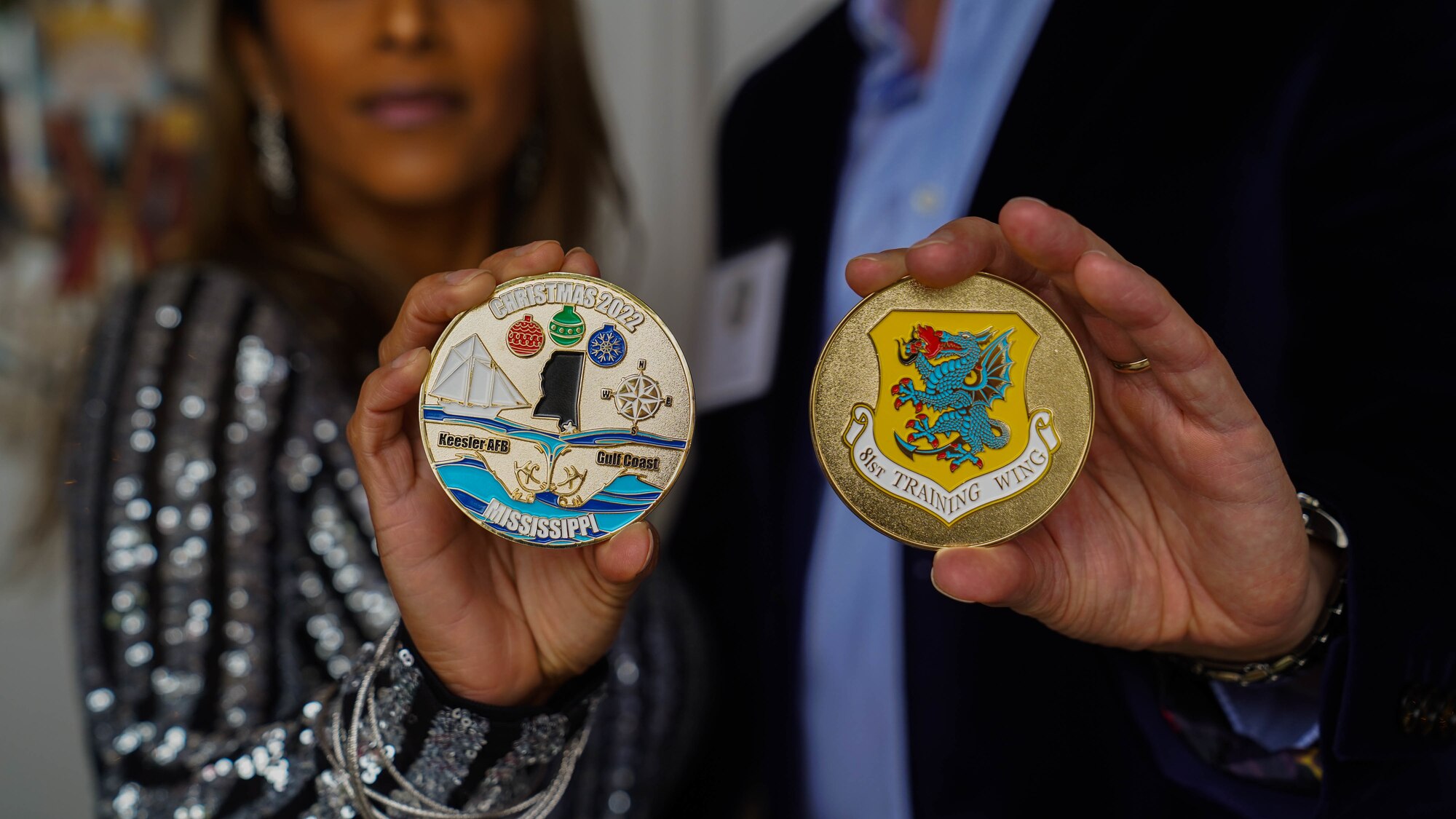 U.S. Air Force Col. William Hunter, 81st Training Wing commander, and his wife, Blanca Hunter, hold up commemorative coins designed by Blanca at the 81st TRW Holiday Open House at Keesler Air Force Base, Mississippi, Dec. 11, 2022.