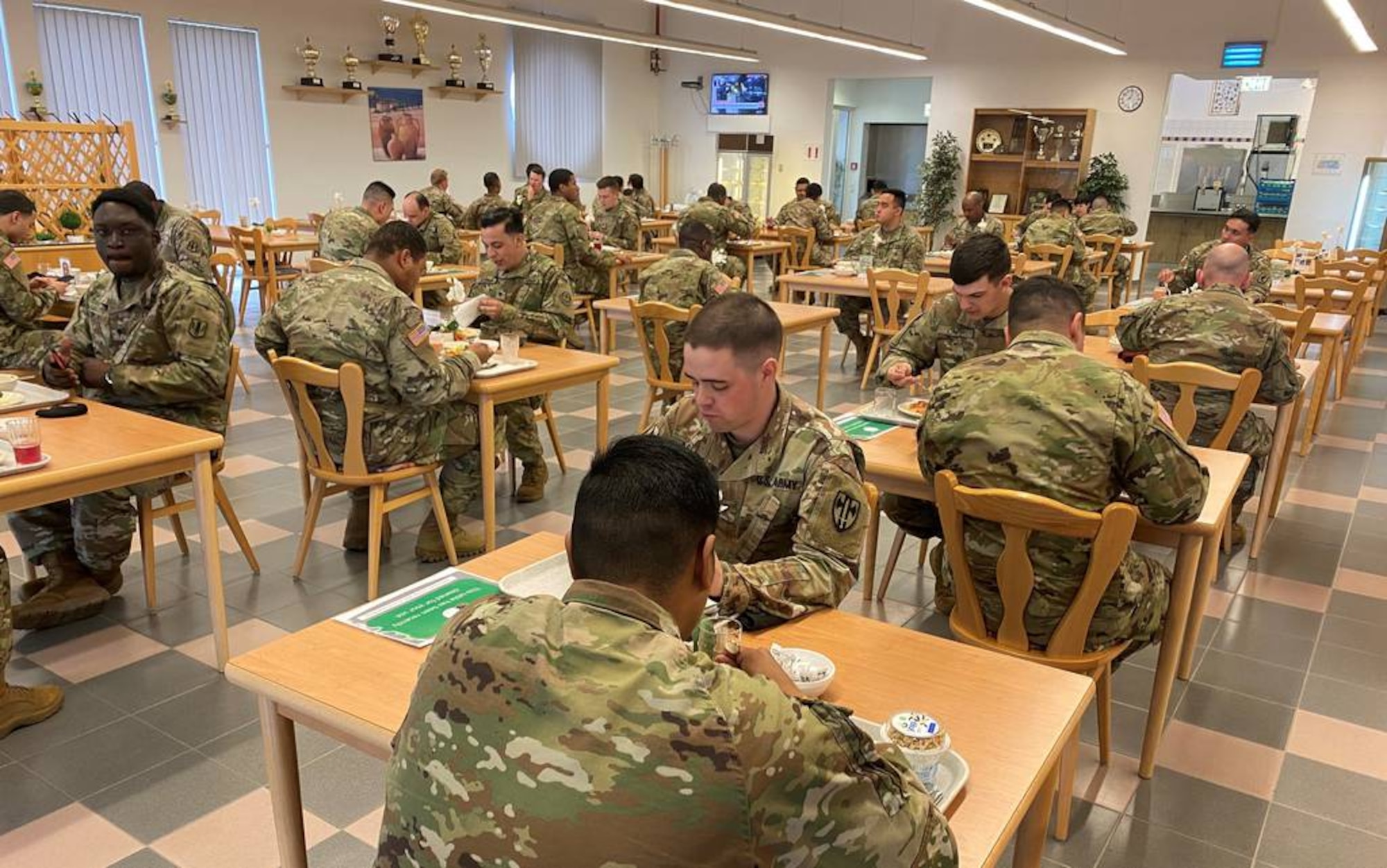 Soldiers sit at tables eating food.