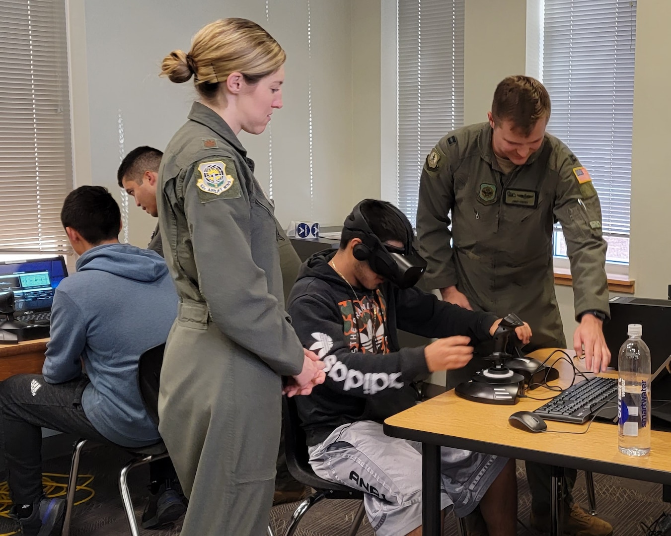 Air Force rated officers help a high student use a flight simulator