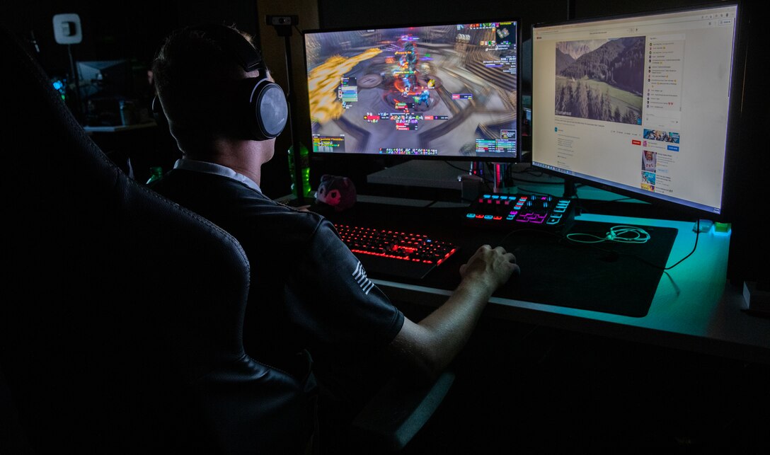 A man faces computer monitors while playing a game.