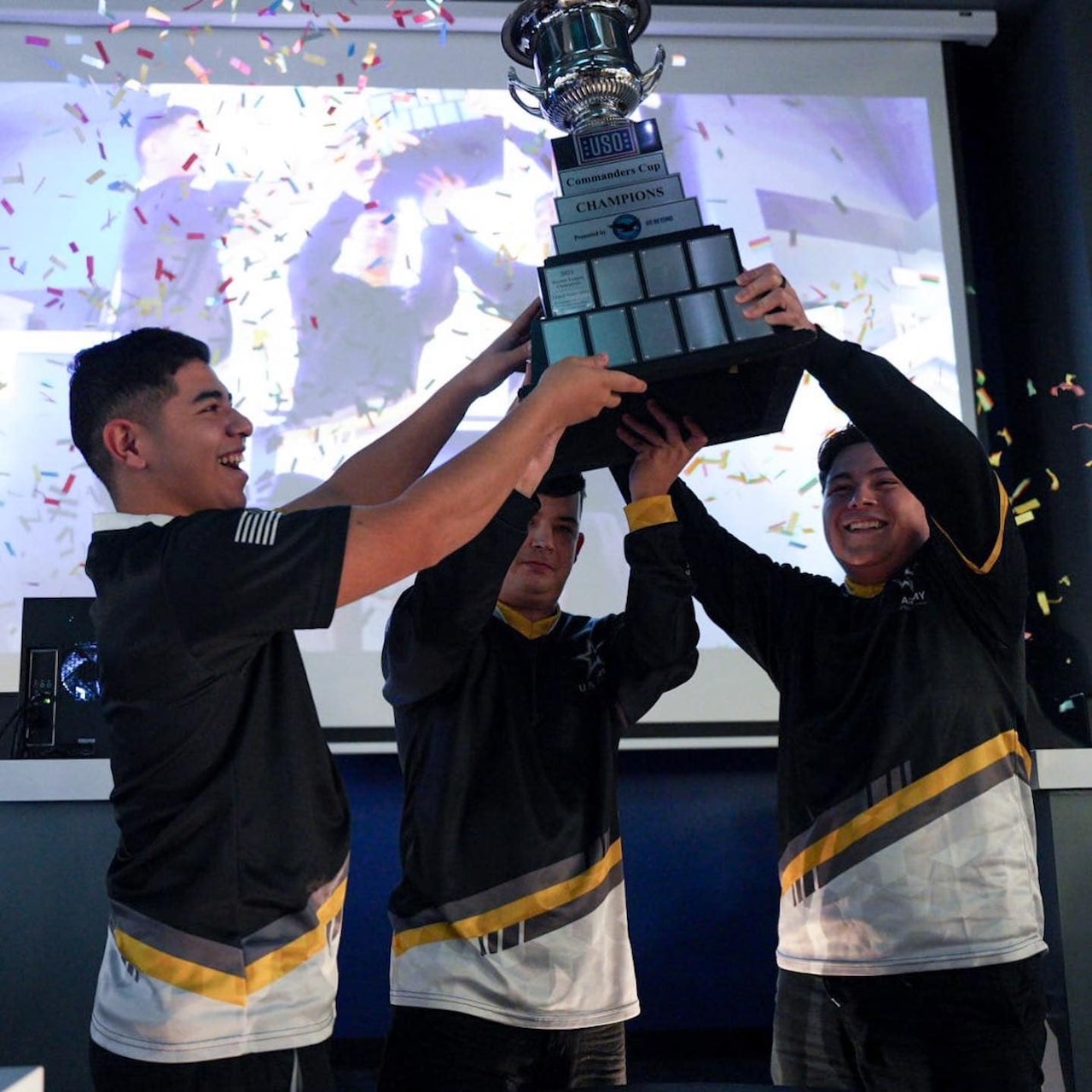 Three men hold up a trophy.