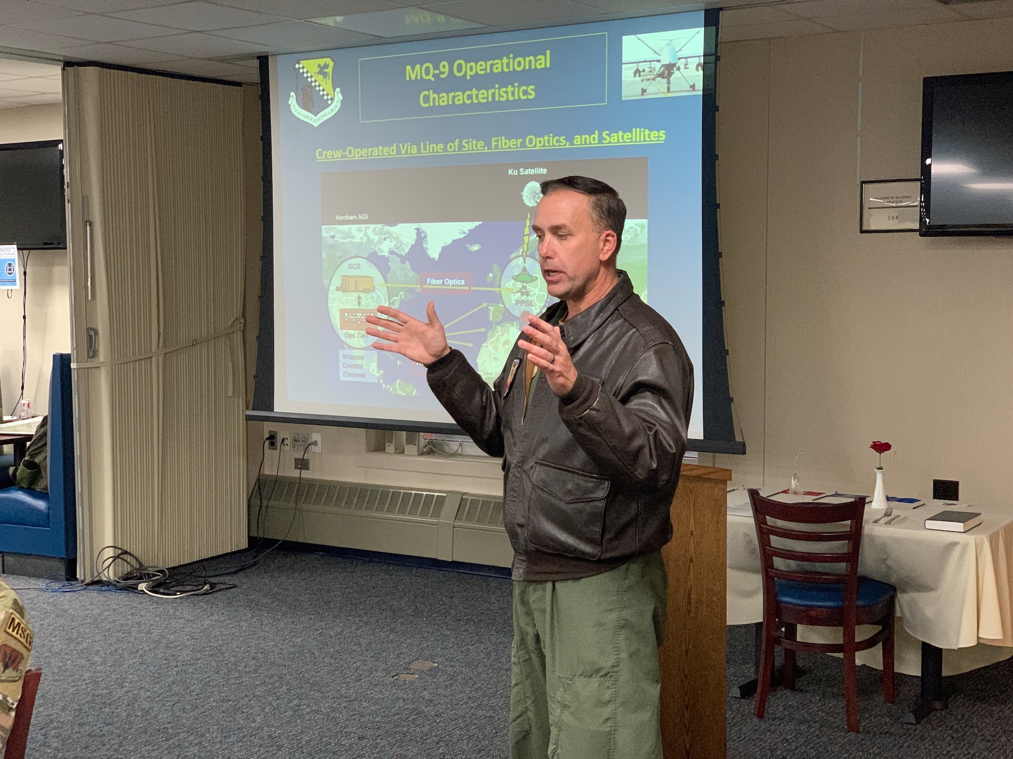 A man in a flight suit and bomber jacket addresses more than 50 community members gathered on base for a quarterly Willow Grove Air Base Restoration Advisory Board (RAB) meeting Dec. 8, 2022.